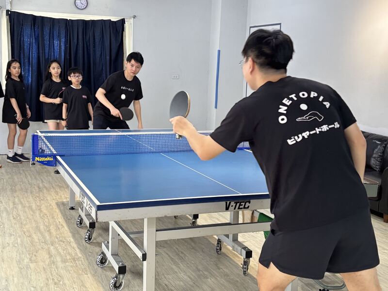 圖:高市青年局長林楷軒(圖後接球者)日前參訪「玩樂倉庫」和創辦人李杰恩交流產業現況,也上場小試身手揮拍練打