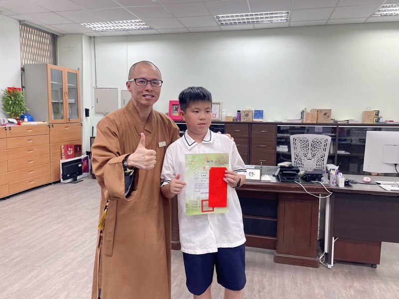 榮獲第二名的五年三班梁榮鑛同學 由南華大學 釋知賢院長頒發獎狀與獎金